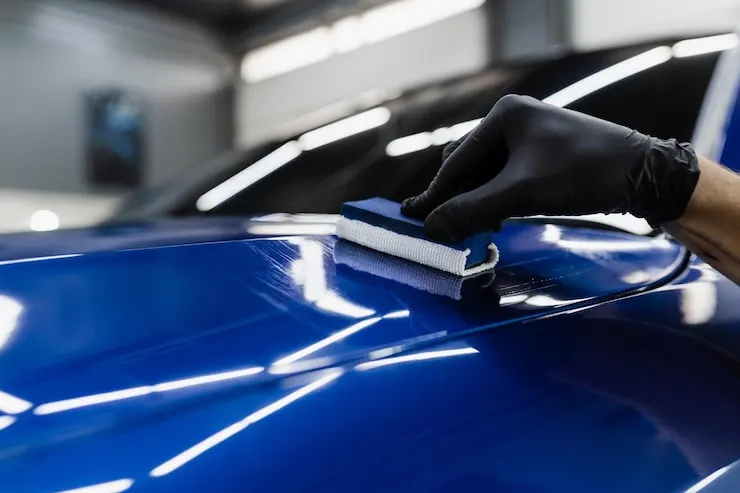 Detailer applying ceramic coating to a blue car hood in Northampton, MA