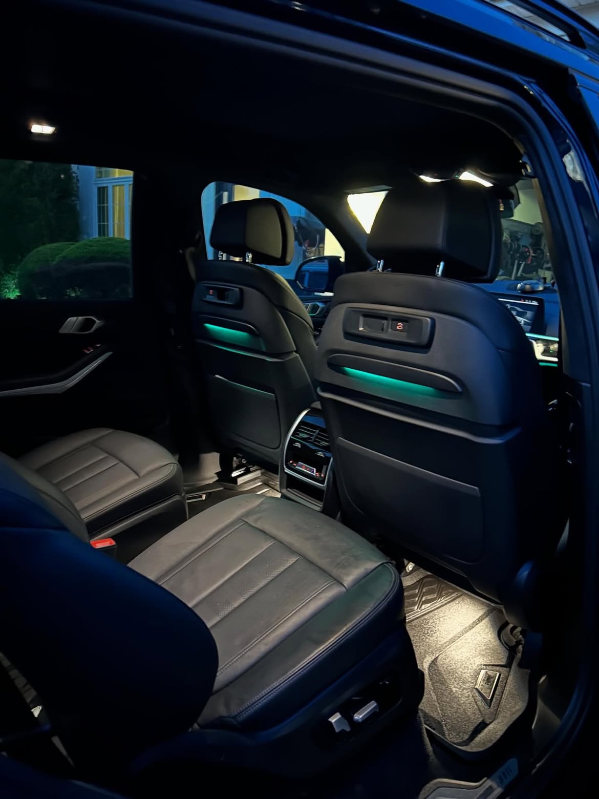 Freshly detailed BMW interior from the rear seat showing clean leather and ambient lighting